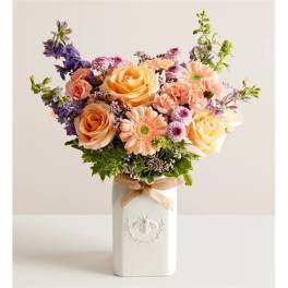 Mixed bouquet of peach roses and pastel daisies in a white vase