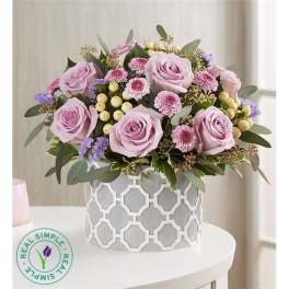 Lavender roses and small pink flowers arranged in a patterned vase