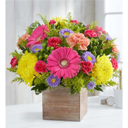 Colorful mixed bouquet in a wooden box with pink, yellow, and purple flowers