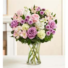 Pink and lavender bouquet of roses, alstroemeria, and carnations in a clear glass vase