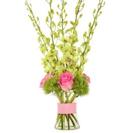 Pink roses and green blooms in a clear glass vase with tall stems.
