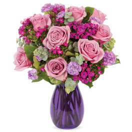 Pink roses and purple flowers arranged in a purple glass vase