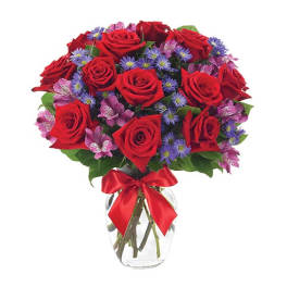 Bouquet of red roses, purple daisies, and pink flowers in a glass vase