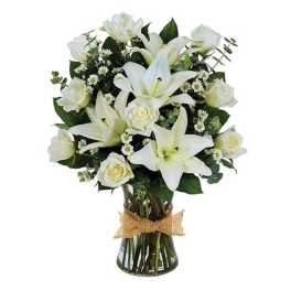 White lilies and roses in a glass vase with a burlap bow