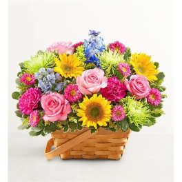Mixed bouquet in a woven basket with pink roses and bright sunflowers