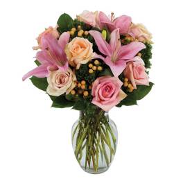 Pink lilies and roses arranged in a clear glass vase