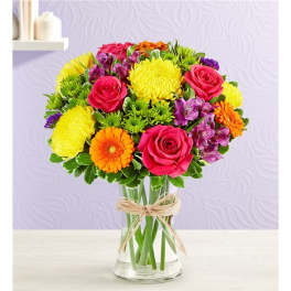 Colorful mixed bouquet of roses, chrysanthemums, and gerbera daisies in a glass vase