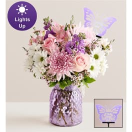Pink, white, and purple bouquet in a faceted lavender vase with a butterfly light