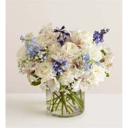 White and blue mixed bouquet in a clear glass vase