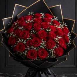 Bouquet of red roses wrapped in black paper with gold trim