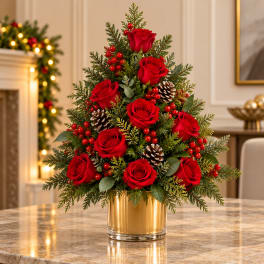 Red roses arranged in a gold vase with pinecones and red berries