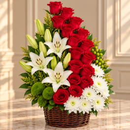 Red roses, white lilies, and white daisies in a wicker basket