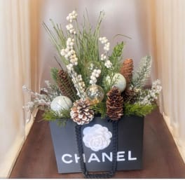 Holiday arrangement in a Chanel gift bag with pinecones and white berries