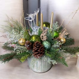 Holiday centerpiece with pine, pinecones, gold candles, and a clear reindeer figurine