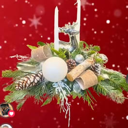 Holiday centerpiece with pinecones, candles, and a silver reindeer on evergreen branches