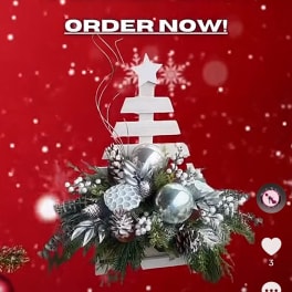 Christmas arrangement with silver ornaments and pine greenery on a white tree-shaped stand