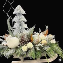 Winter floral centerpiece with white flowers and pinecones on a sled