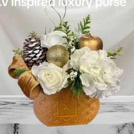 White flowers arranged in a gold monogrammed vase with pinecones and ornaments