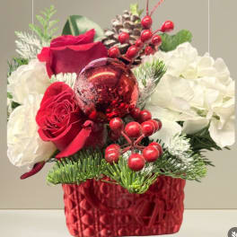 Red and white roses with holiday berries in a red vase