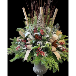Holiday arrangement with evergreen branches, red berries, and ribbon in a gray urn