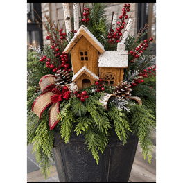 Holiday planter with faux houses, pinecones, berries, and evergreen branches in a black pot