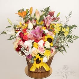 Mixed bouquet in a wicker basket with lilies, roses, and sunflowers