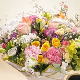 Mixed bouquet of roses, carnations, and lilies in white wrap