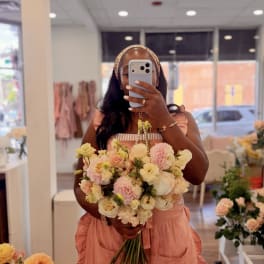 Woman holding a pastel bouquet of roses and carnations in a flower shop