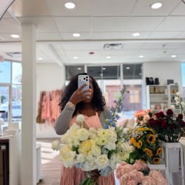 Woman holding a large bouquet of white and pale yellow flowers in a shop