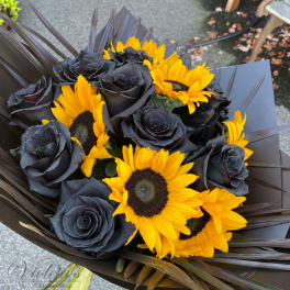 Bouquet of black roses and bright yellow sunflowers wrapped in dark paper