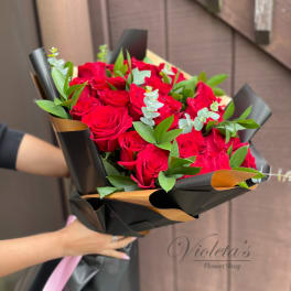 Bouquet of red roses wrapped in black paper with green foliage