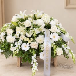 White floral arrangement with roses and lilies in a low wooden stand