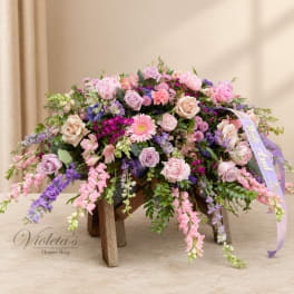 Large pastel flower arrangement on a wooden stand with a ribbon