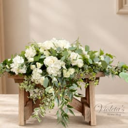 White rose arrangement with cascading greenery on a wooden stand