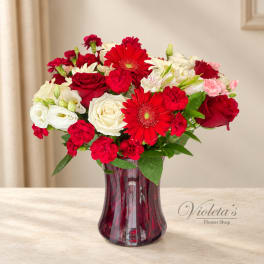 Red and white mixed bouquet in a burgundy glass vase