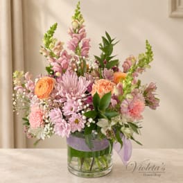 Pastel mixed bouquet in a clear glass vase with a lavender ribbon