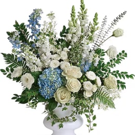 White and blue floral arrangement in a white pedestal vase