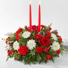 Red candle centerpiece with white and red flowers and pinecones