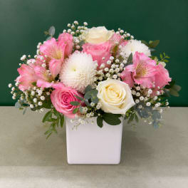 Pink and white flower arrangement in a white square vase