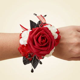 Red rose wrist corsage with white accents and ribbon on a wrist