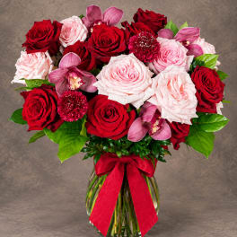 Bouquet of red and pale pink roses with orchids in a glass vase