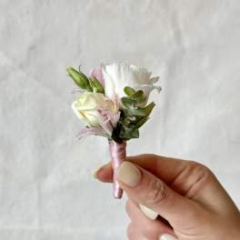 Small boutonniere with white and pale pink flowers wrapped in pink ribbon