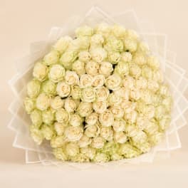 Large bouquet of cream and pale yellow roses wrapped in translucent paper