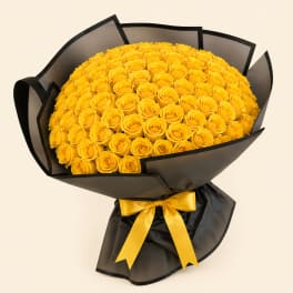 Large bouquet of yellow roses wrapped in black paper with a yellow ribbon