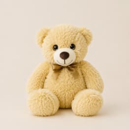 Plush teddy bear with a ribbon bow on a plain background