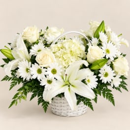 White lilies, roses, and daisies arranged in a white basket