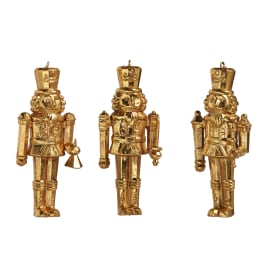 Three gold nutcracker ornaments on a white background