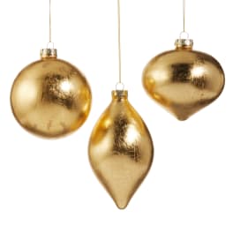 Three gold Christmas ornaments hanging on white background