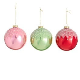 Three glitter-topped Christmas ornaments in pink, green, and red