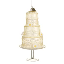 Three-tier ivory cake ornament on a glass stand with small white flowers